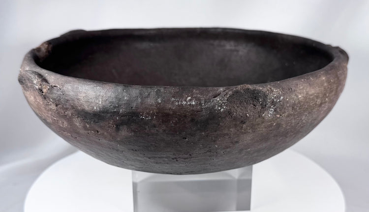 Hand-formed ancient pottery bowl with rim projections and mineralized archaeological surface