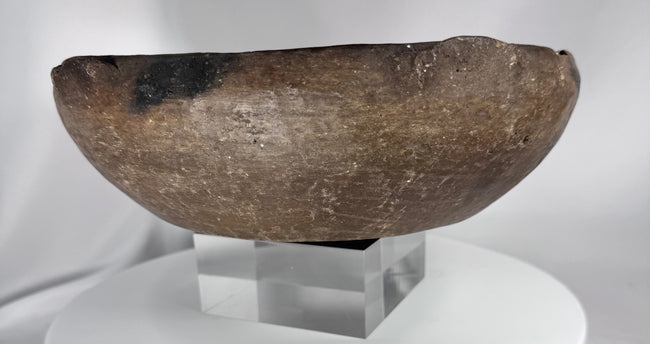 Ancient ceramic serving vessel with dark mineral deposits and thick reinforced rim