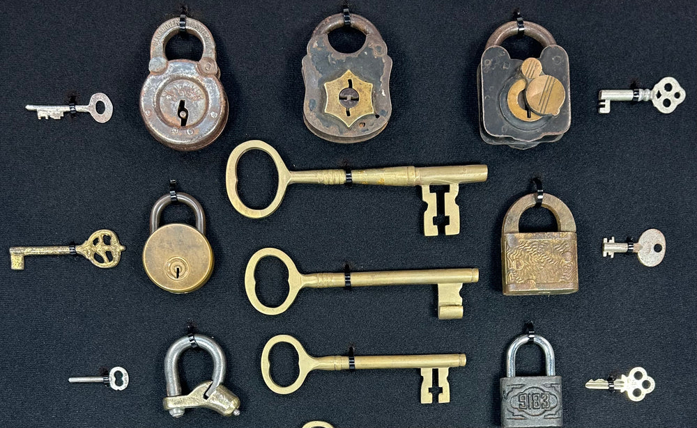 Historic lock collection with mixed metal padlocks and keys arranged in museum-style display frame