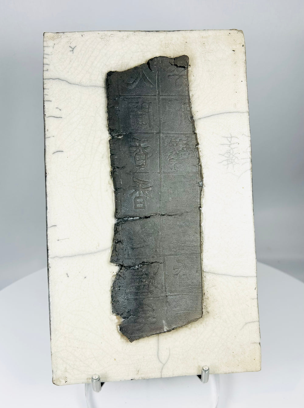 Chinese inscribed ceramic fragment displayed on stand highlighting texture, patina, and incised characters