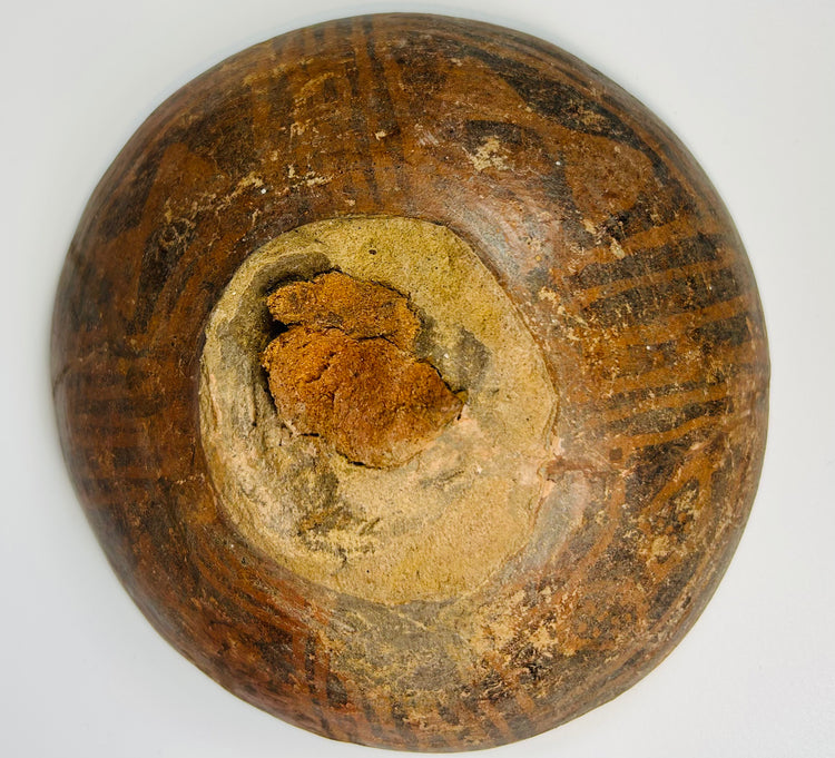 Ancient pottery bowl with dark geometric motifs on earthen background from Mesoamerican culture