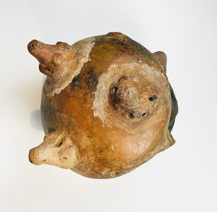 Ancient ceramic tripod bowl with orange slip and visible wear from burial