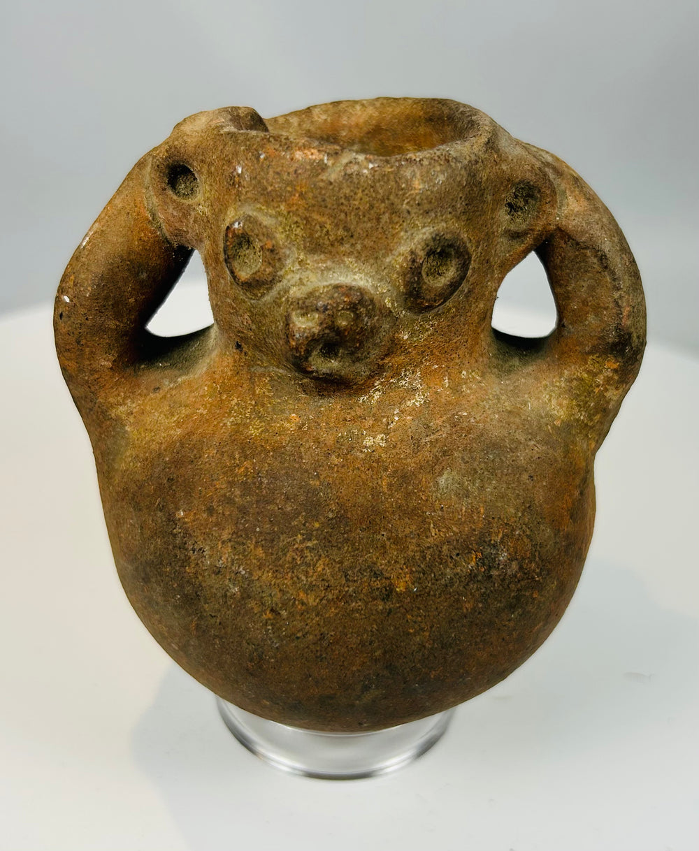 Pre-Columbian zoomorphic effigy vessel with sculpted face and dual loop handles showing heavy patina