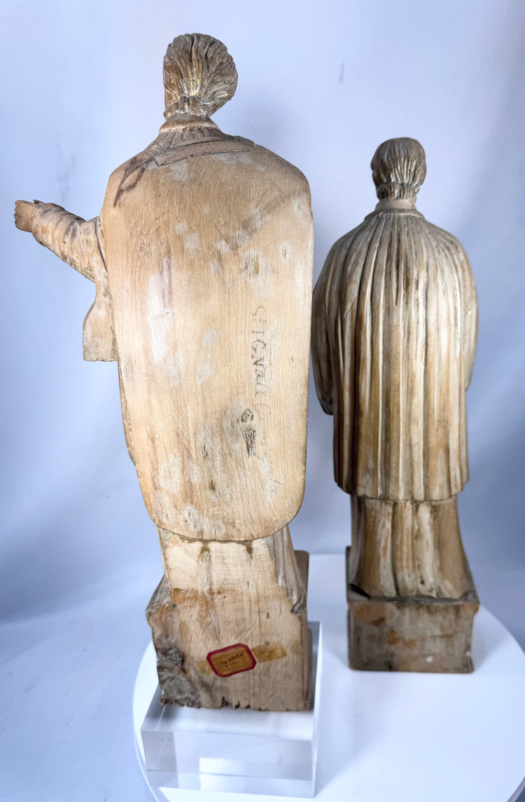 Hand-carved Christian saint figures in wood featuring detailed vestments and expressive facial features.
