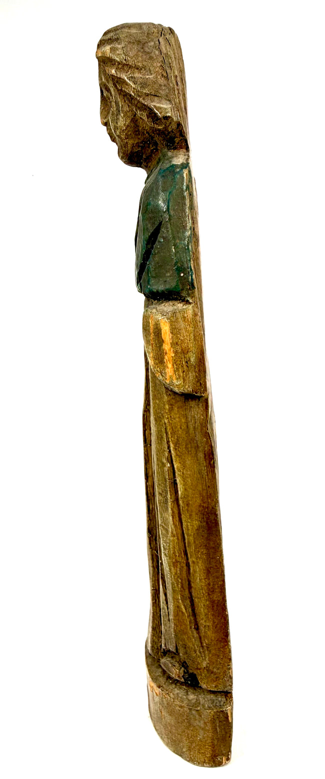 Left side view of weathered wooden folk art statue with remnants of green paint