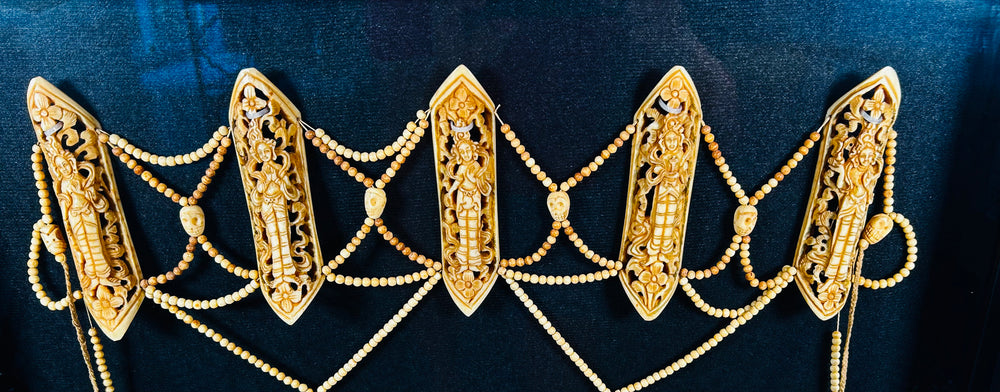 19th-century Tibetan Tantric ritual bone apron (rus gyan) displayed in black frame, featuring six carved bone plaques depicting Chakrasamvara deities, intricate bead lattice, cotton backing, and natural pigments — sacred Himalayan Buddhist ceremonial garment.