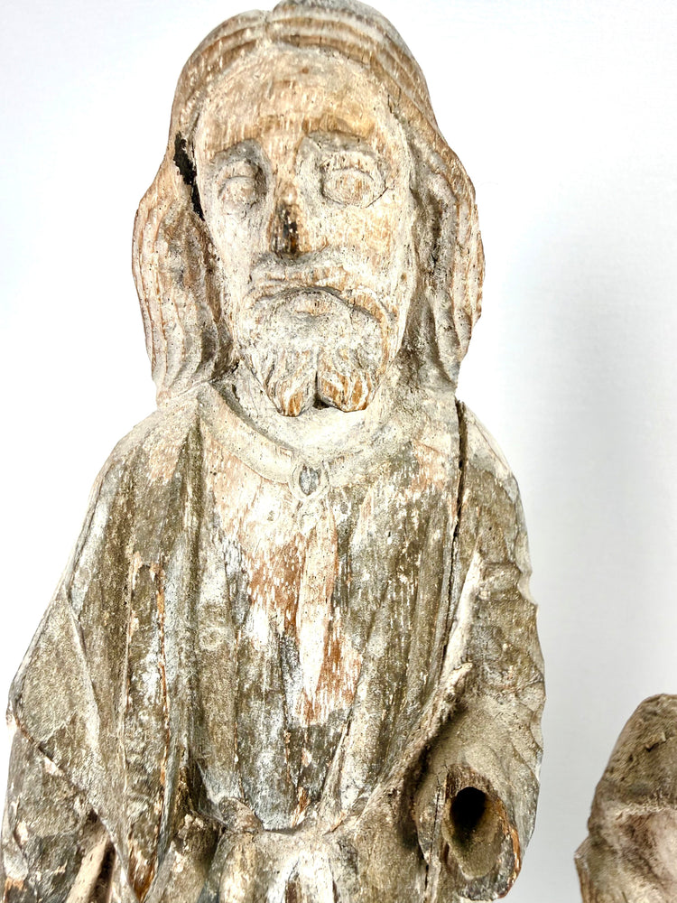 Close-up of weathered hand-carved wood Santo figure with faded white paint and natural patina