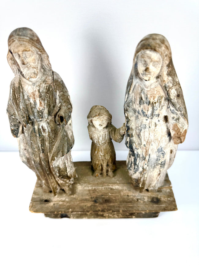 High-angle view of aged wood religious statues showing rough texture and connected hands