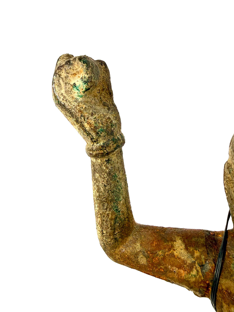 Close-up of raised arm showing green verdigris corrosion on bronze