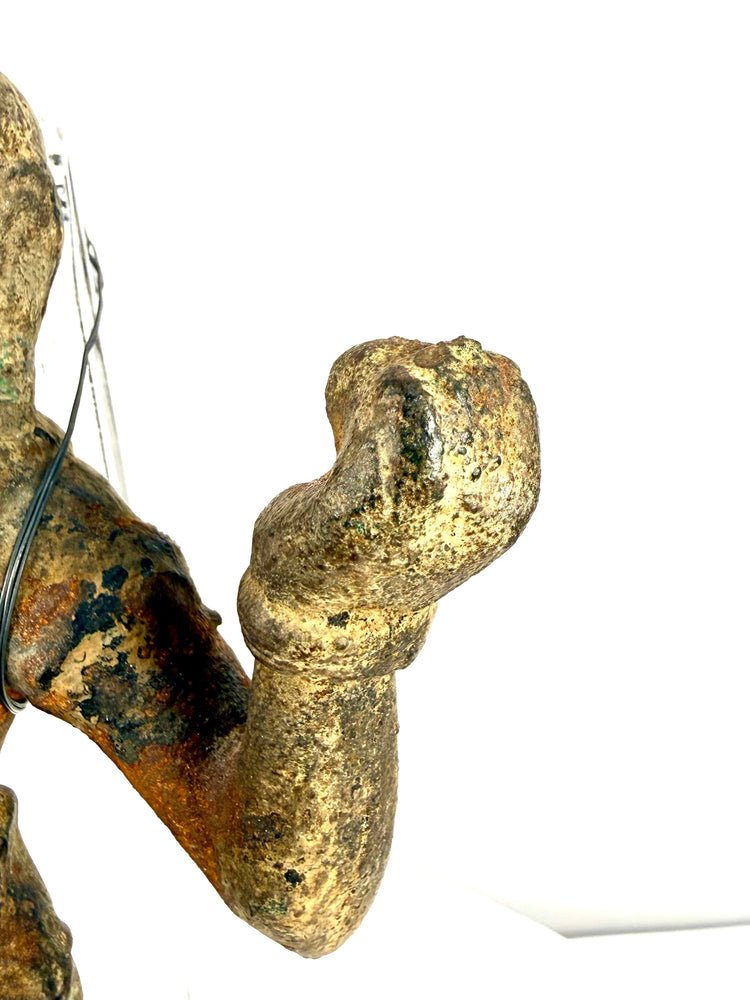 Macro detail of pitted bronze hand and wrist with mounting wires