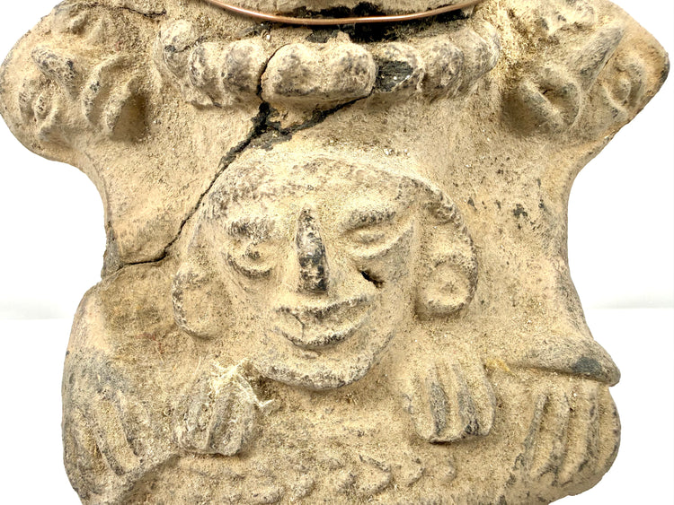 Close-up of lower sculpted face on beige earthenware with hand reliefs and fracture line