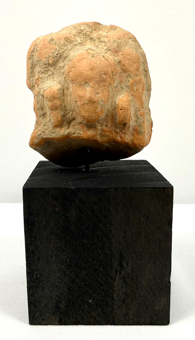 Full frontal view of ancient terracotta bust centered on tall black display block