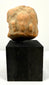 Full frontal view of ancient terracotta bust centered on tall black display block