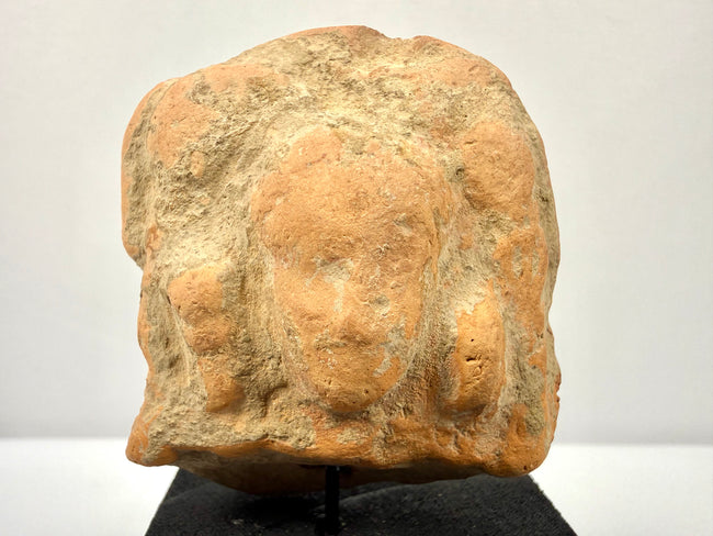 Direct close-up of Gandharan terracotta fragment emphasizing central bust relief