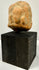 Frontal view of ancient orange-brown terracotta plaque with central bust and side figures