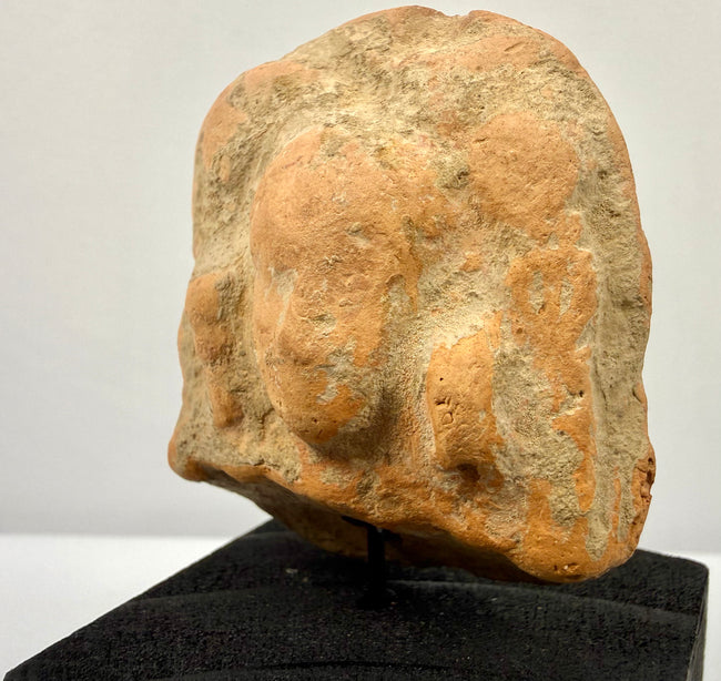 Angled close-up of terracotta face revealing worn nose and rounded headdress details