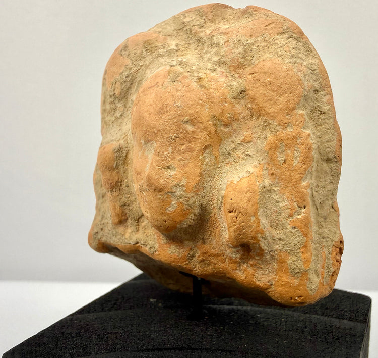 Angled close-up of terracotta face revealing worn nose and rounded headdress details