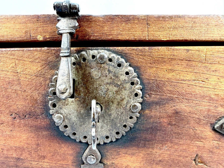 Close-up of circular hand-forged iron lock plate with scalloped edge and raised metal slide bolt mechanism