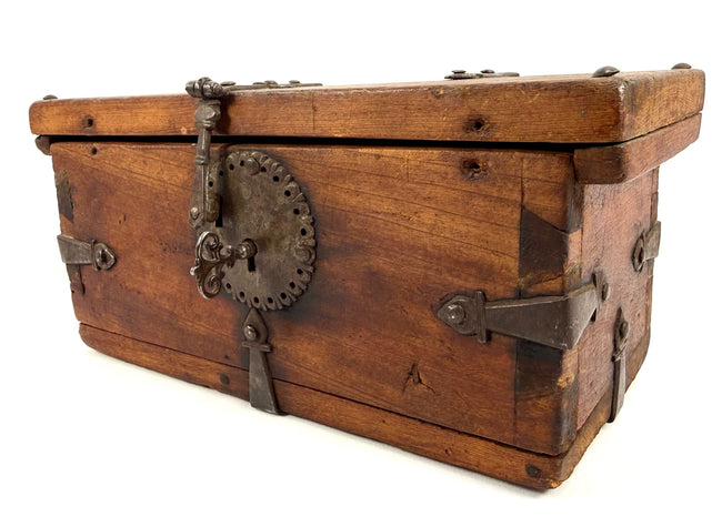 Side view of elmwood strongbox showing heavy iron bracing, strap hinges, and decorative circular lock escutcheon