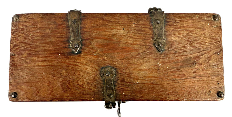 Bottom view of antique wooden strongbox displaying natural wood grain and four rounded iron foot studs