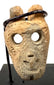 Ancient Mesoamerican anthropomorphic bone pendant featuring a stylized human face, recessed eyes, and twin suspension holes.