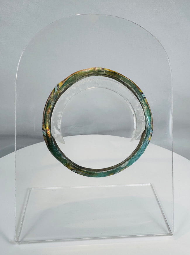 Ancient Roman polychrome glass bracelet displaying intricate striped decoration and archaeological iridescence.