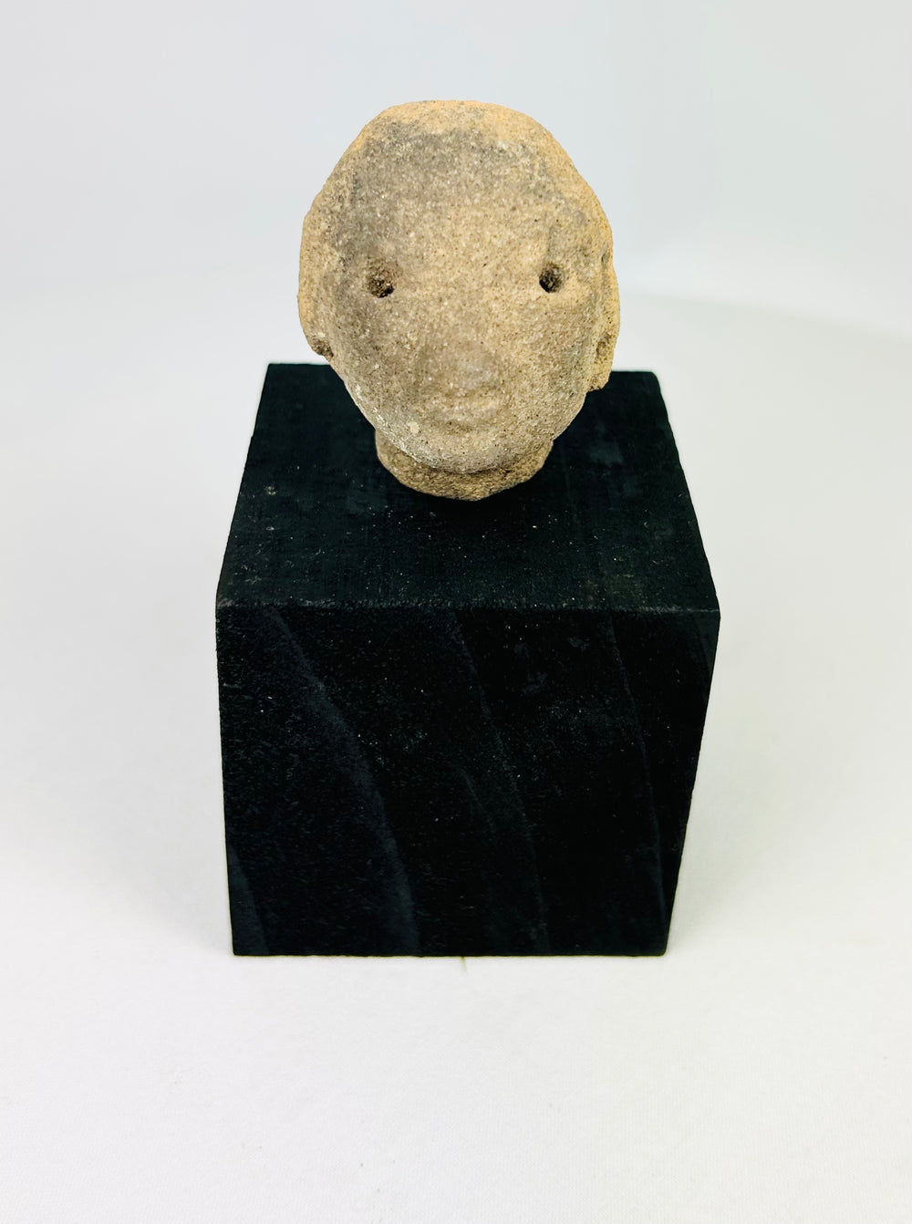 Terracotta head fragment, West Mexico, Pre-Columbian era, with drilled eyes and soft facial features, circa 300 BCE–300 CE, on black display stand