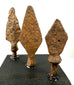 Elongated asymmetrical iron projectile point with a narrow blade, irregular edges, and reddish-brown oxidation.