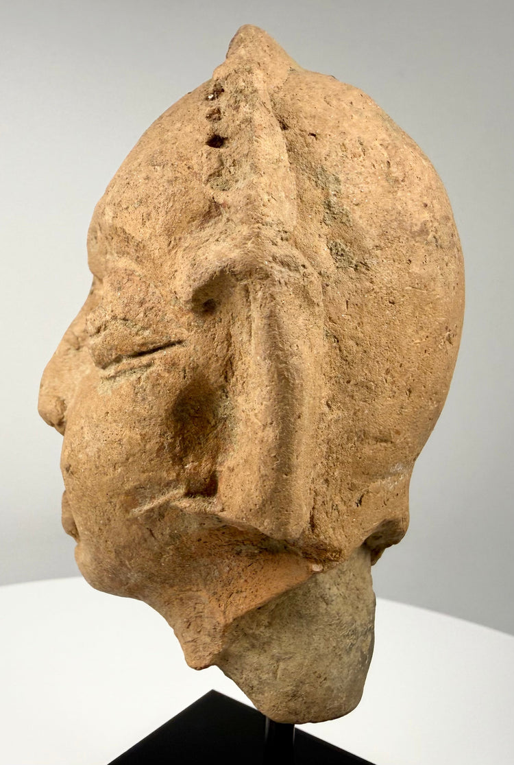 Historic Indian terracotta head fragment measuring approximately 5.5 inches tall, mounted on a modern black display stand.