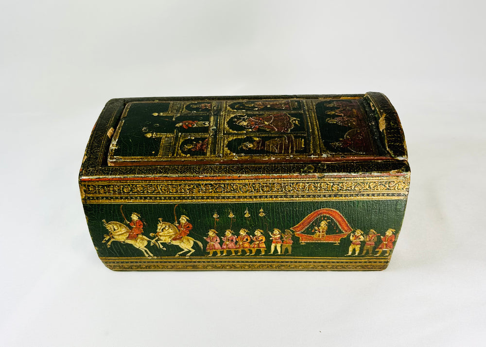 19th-century Indian Ganjifa storage box with hand-painted procession scene on a green background, photographed on a white backdrop.
