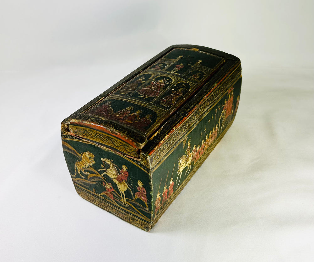 Angled view of a 19th-century Indian Ganjifa playing card box with polychrome palace and procession artwork, on a white background.