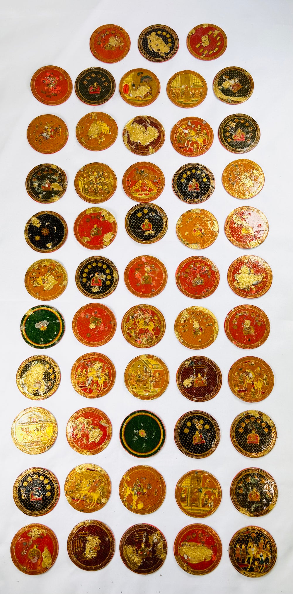 Collection of 19th-century Indian Ganjifa playing cards arranged in rows, showing colorful hand-painted round card designs on a white background.