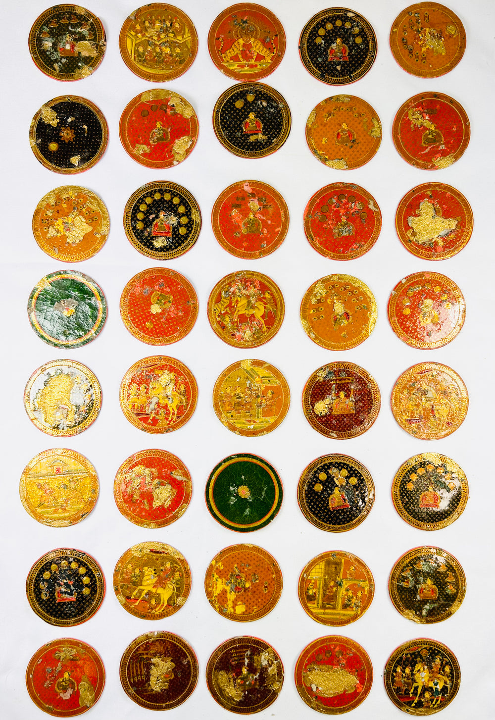 Large grouping of 19th-century Indian Ganjifa round cards arranged in rows, showcasing vibrant hand-painted motifs on a white backdrop.
