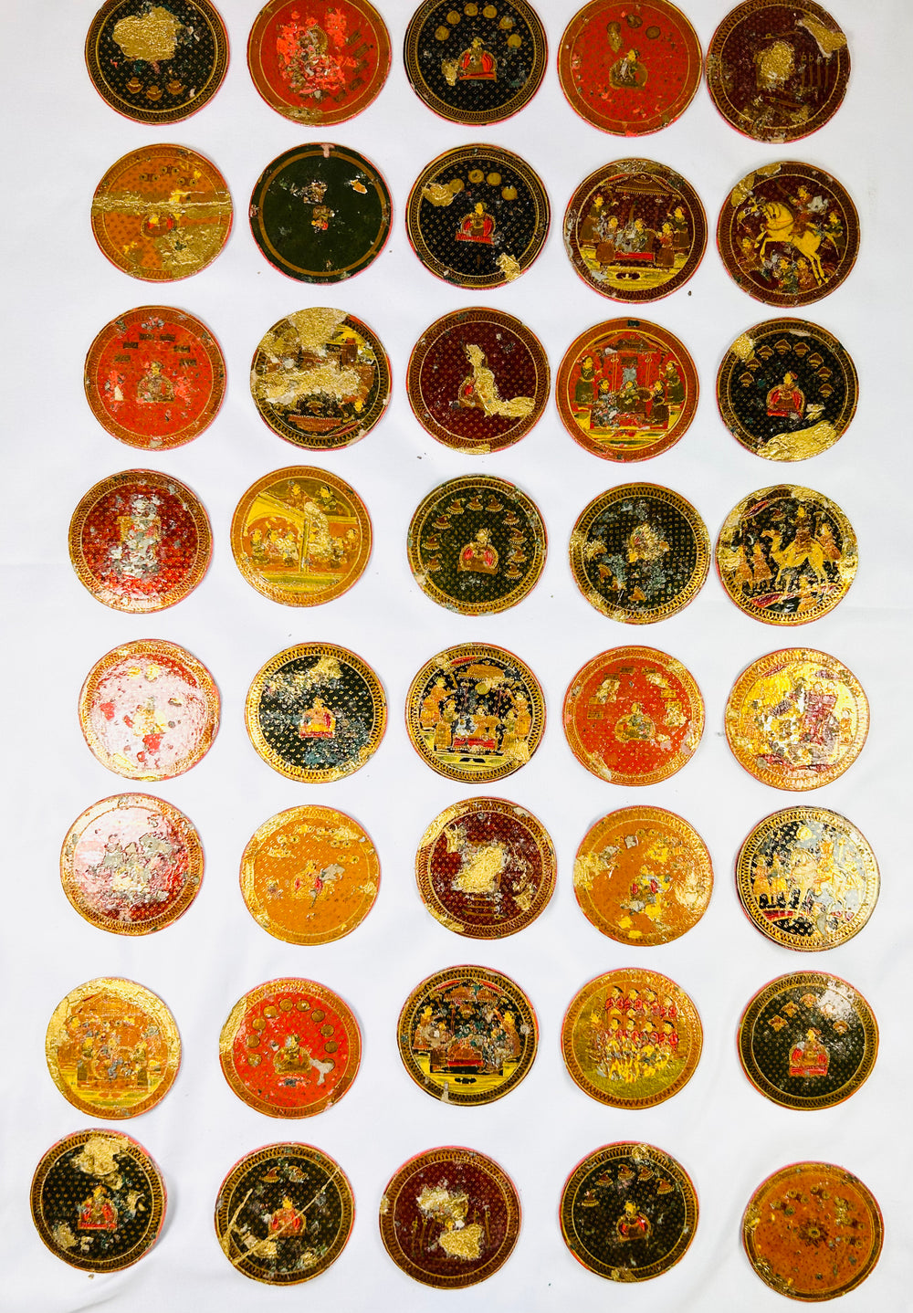 Collection of 19th-century Indian Ganjifa circular cards with detailed miniature artwork and varied color palettes, laid out on a white background.