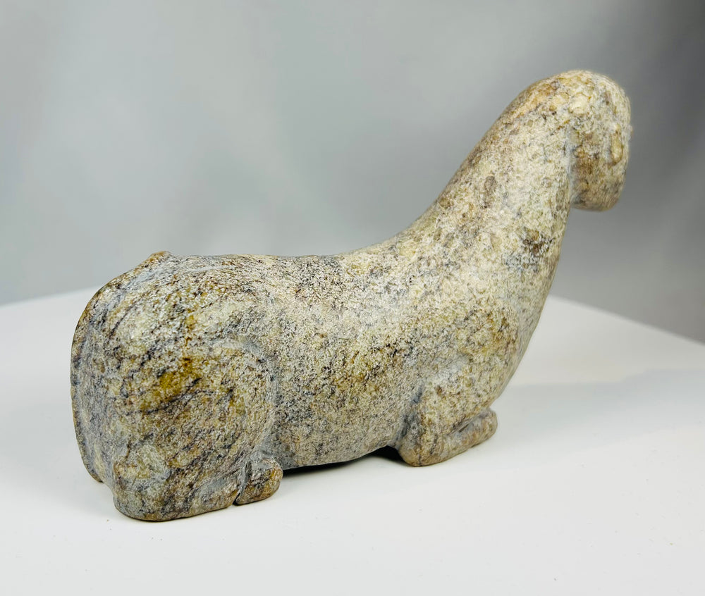 Carved stone animal effigy with elongated proportions and simplified features