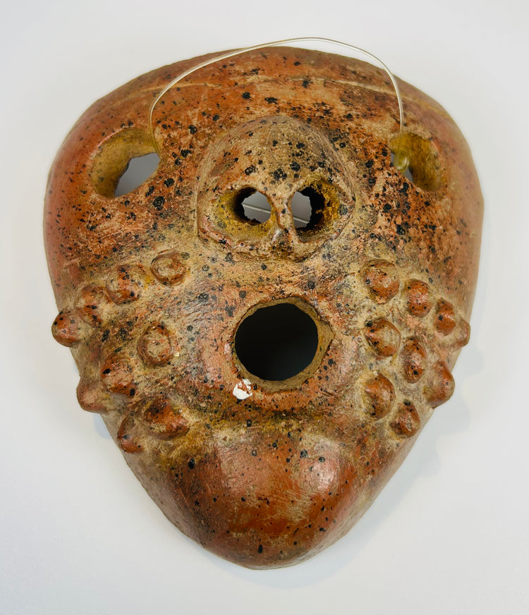 Pre-Columbian ceramic mask with stylized facial features and mineral deposits