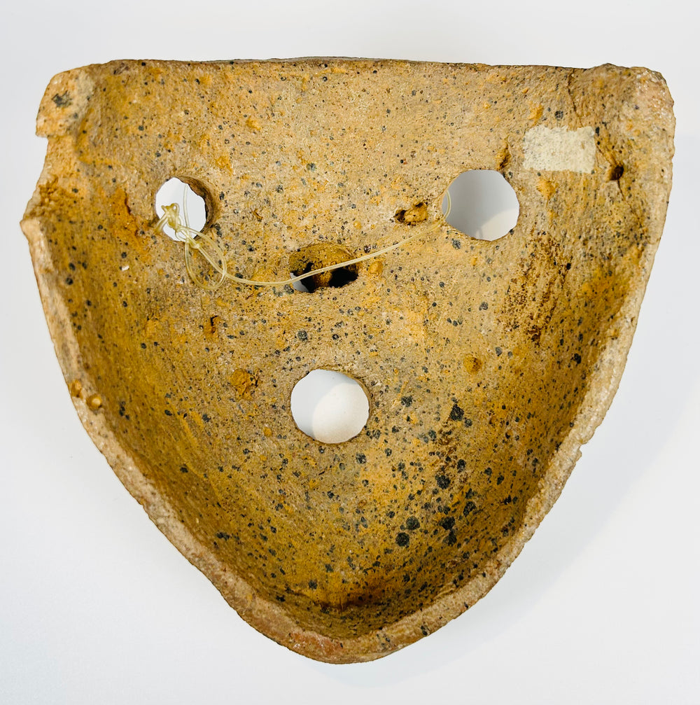 Mesoamerican clay mask with bold features and burial encrustation