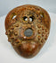 Ancient terracotta mask with geometric facial design and patina