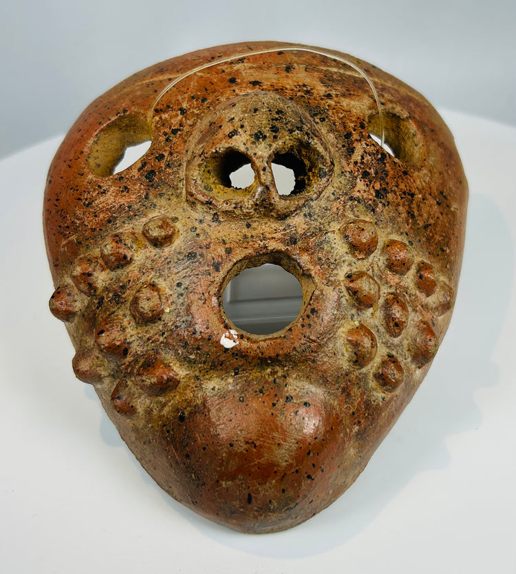 Ancient terracotta mask with geometric facial design and patina
