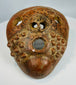 Ancient terracotta mask with geometric facial design and patina