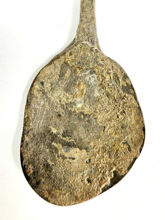 Close-up of an ancient Roman bronze spoon highlighting its spiral-twisted handle and naturally aged patina.