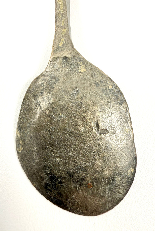 Detailed view of an ancient Roman dining utensil featuring dark green and brown bronze patination.