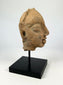 Angled right-front view of an ancient Gupta terracotta head fragment displayed on a black stand.
