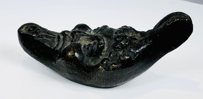 Antique cast metal oil lamp in the form of a satyr head with filling aperture and wick nozzle.