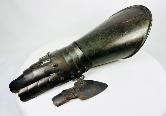 Steel battlefield-style gauntlet with overlapping finger plates and flared cuff, museum-quality photograph.