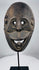 Indonesian ritual mask from West Timor with pierced eyes, open mouth, and weathered carved wood surface.