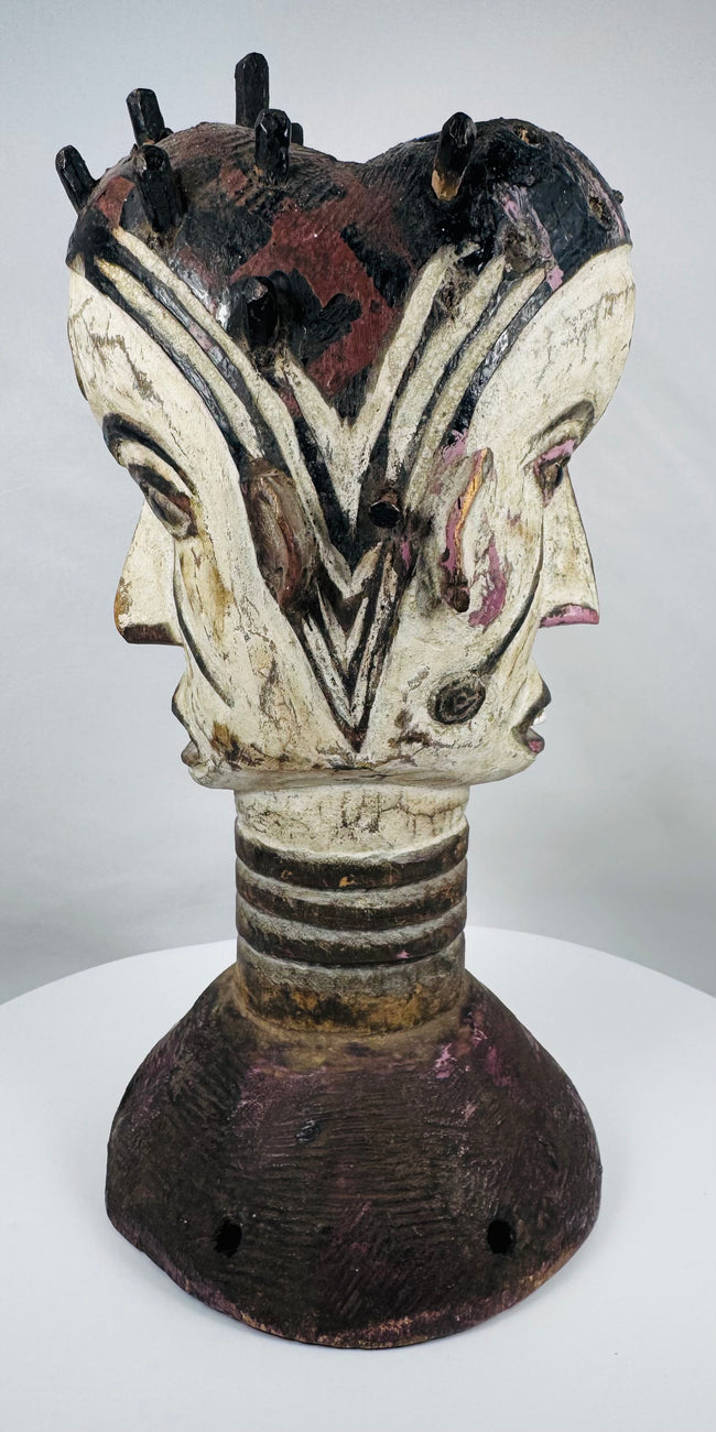 Traditional Igbo masquerade crest with opposing faces, projecting coiffure elements, and aged patina.