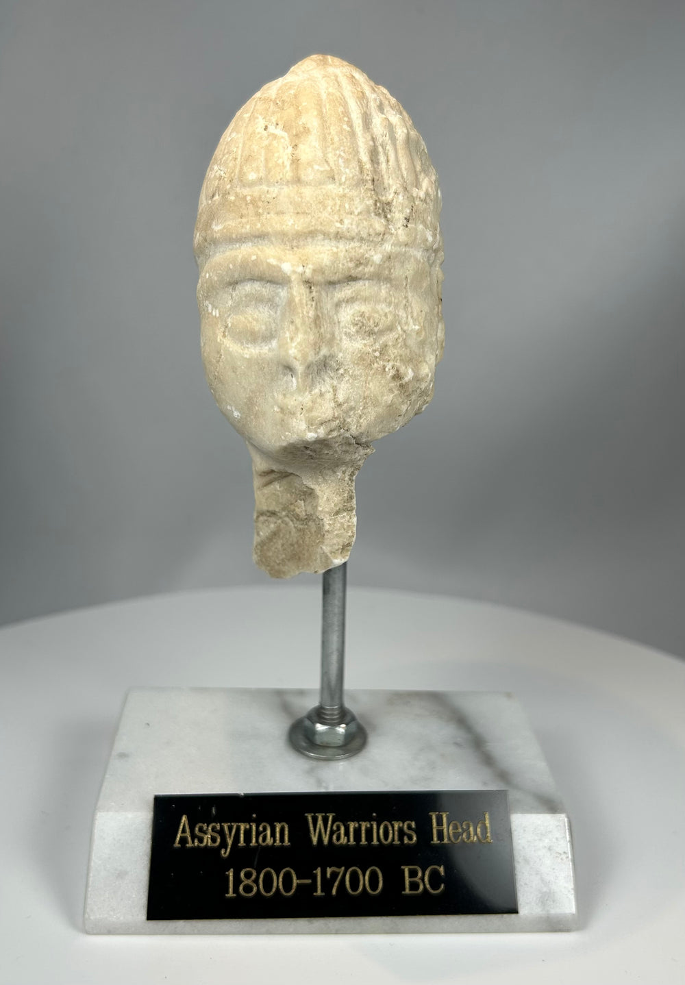 Ancient Near Eastern stone head with helmet and weathered surface