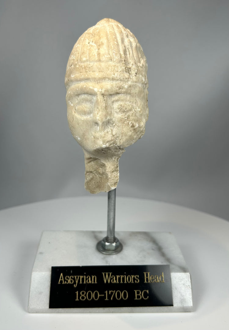 Ancient Near Eastern stone head with helmet and weathered surface