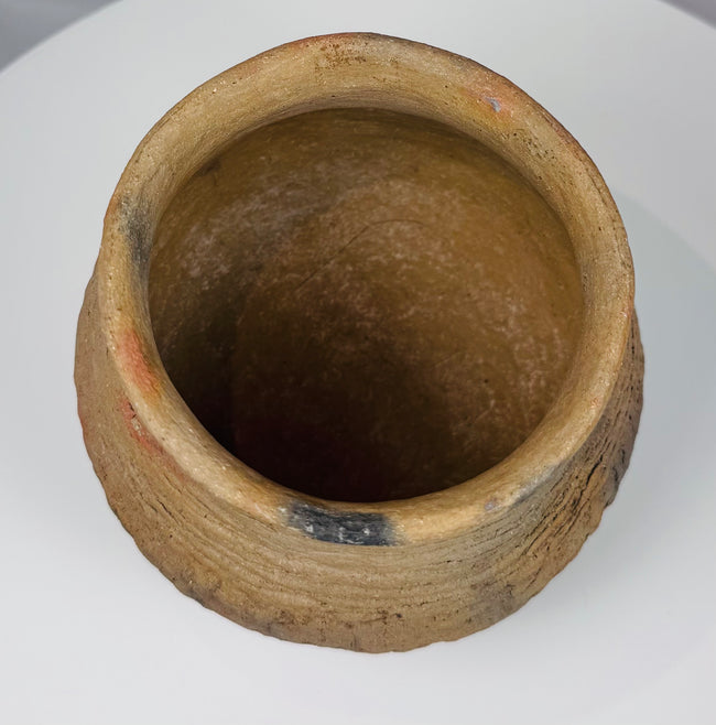 Ancient Casas Grandes storage vessel with rounded form, textured surface, and horizontal corrugated decoration around the upper body.